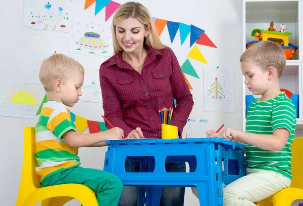 Children with mom and draw pictures in the kids room. — Stock Photo, Image
