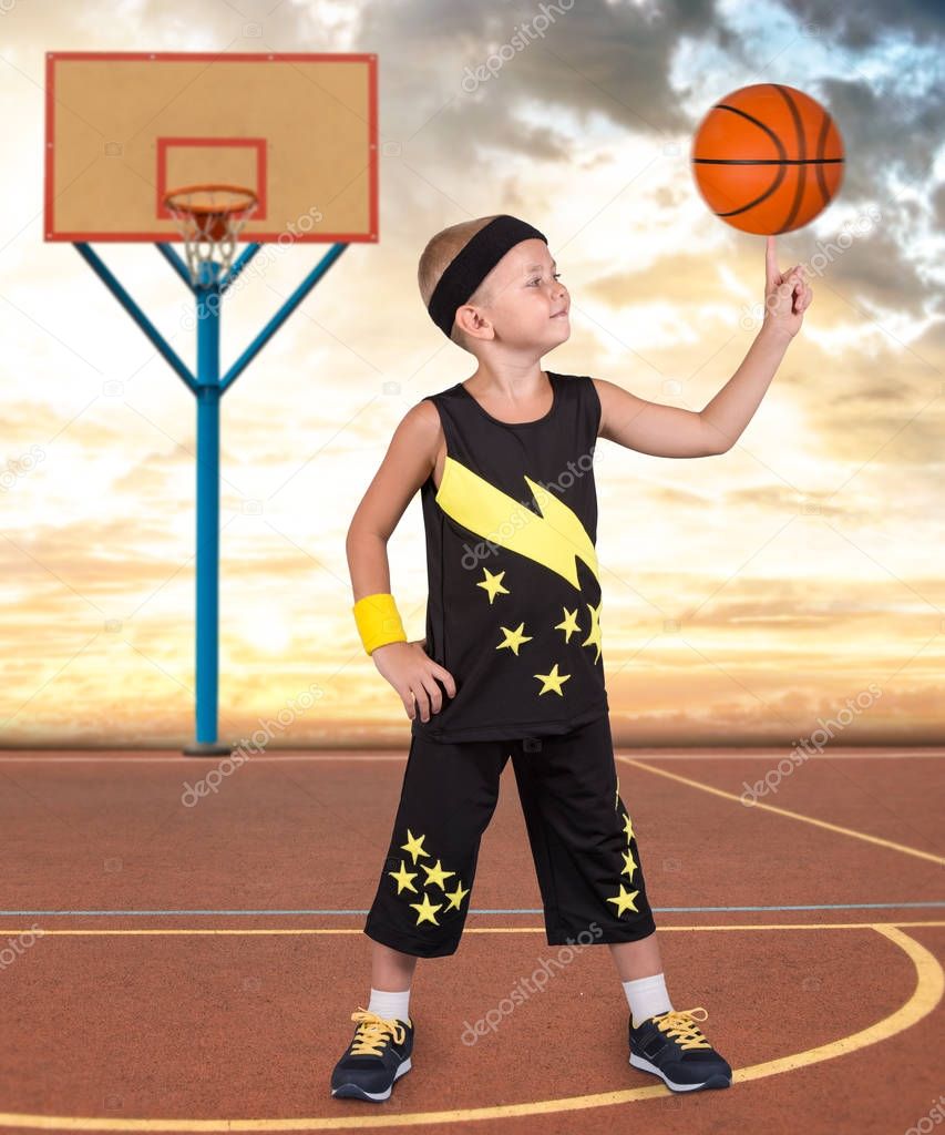 Child playing in street basketball. Boy spinning the ball on his finger.