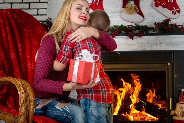 Kellemes karácsonyi ünnepeket és boldog ünnepek! Aranyos fiú ad szeretett édesanyja egy ajándék. A nappaliban belső újévi. — Stock Fotó