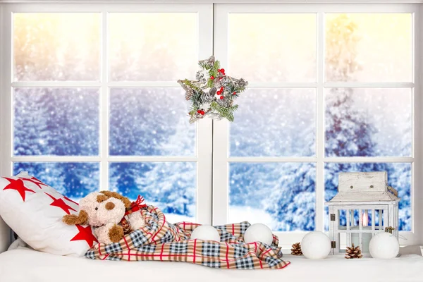 Kellemes karácsonyi ünnepeket és boldog ünnepek! Karácsonyi dekoráció az ablakban, játékszer kutya alszik egy párna, egy takaró alatt. — Stock Fotó