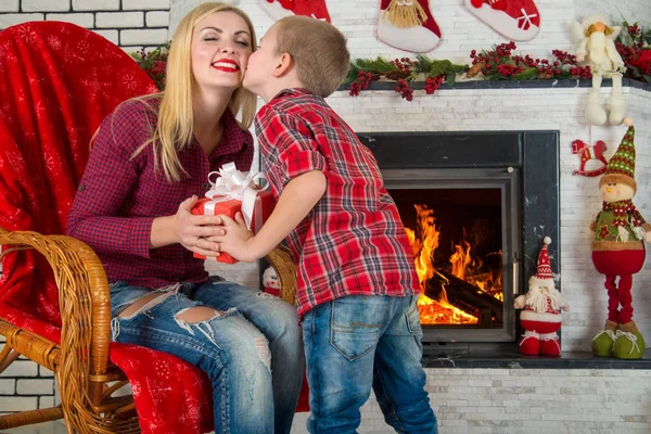 Kellemes karácsonyi ünnepeket és boldog ünnepek! Aranyos fiú ad szeretett édesanyja egy ajándék. A nappaliban belső újévi. — Stock Fotó