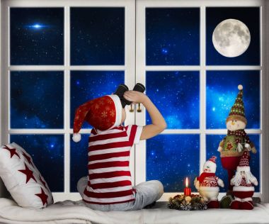 Mutlu Noeller ve mutlu tatiller! Çocuk pencere pervazına ve dürbün bakarak oturur. Çocuk tatil keyfini çıkarın. Noel gösterge kavramı.