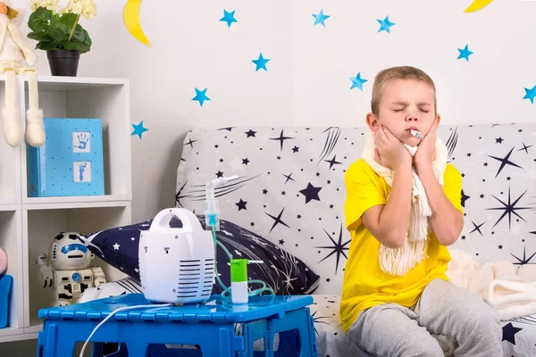 The little boy feels pain in the throat, measures the temperature.Child makes inhalation nebulizer . — стоковое фото