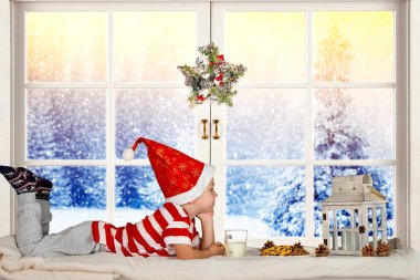 Mutlu Noeller ve mutlu tatiller! Dinlenme, Noel Baba'yı bekleyen penceresinde oturan küçük bir çocuk.