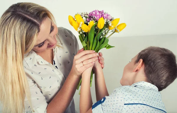 Son gives his beloved mother a beautiful bouquet of tulips.The concept of the celebration,women's day.