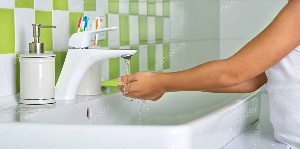 Child washing hands with soap in the bathroom.