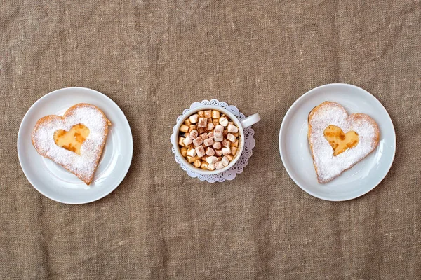 Cheese pancake in the form of a heart and a cup of coffee with marshmallows. Romantic breakfast.