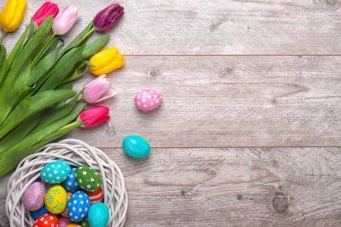 Paskalya yumurtaları ahşap arka plan üzerinde renkli Lale ile hasır sepetin içinde. Paskalya tatil kavramı.