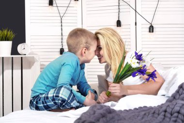 Çocuk anne kadar uyanır ve ona yatakta bir buket çiçek verir. Kadın Day.Mother'ın günü kutlama.