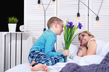 Çocuk anne kadar uyanır ve ona yatakta bir buket çiçek verir. Kadın Day.Mother'ın günü kutlama.