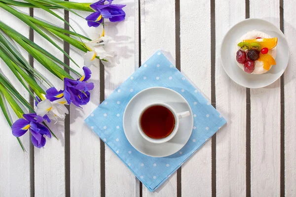 Delicious dessert, fragrant tea and a bouquet of irises on a wooden table.Concept of holidays.