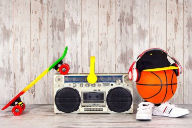 Müzik Hip hop tarzı ve spor kavram. Kulaklıklar, modaya uygun kap, spor ayakkabı, basketbol topu, kaykay ile Vintage ses çalar.