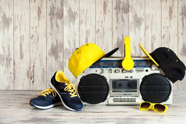 The concept of the music Hip hop style.Vintage audio player with headphones,fashionable cap, sneakers and sunglasses.