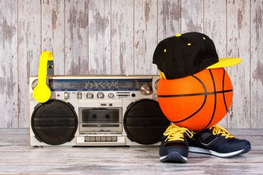 Müzik Hip hop tarzı ve spor kavram. Basketbol topu, spor ayakkabı, moda kap ve kulaklık ile Vintage müzik çalar.