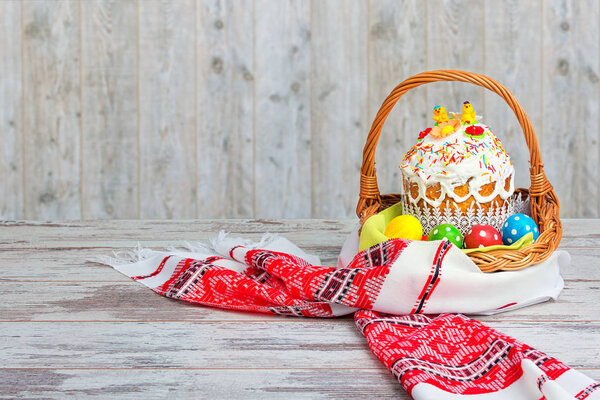 Happy Easter! Easter Cake - Russian and Ukrainian traditional kulich and colorful eggs in a wicker basket on an embroidered towel.