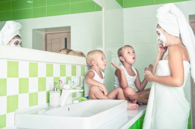 Anne ve çocuklar sabah yüz maskesi yapıyorlar. Çocuklar anneleriyle şakalaşıyor. Cilt için güzellik tedavileri