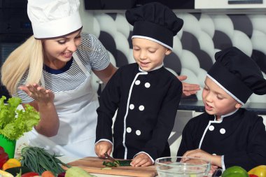 Bir aşçı ailesi. Sağlıklı beslenme. Mutlu aile anne ve çocukları mutfakta sebze salatası hazırlıyor.