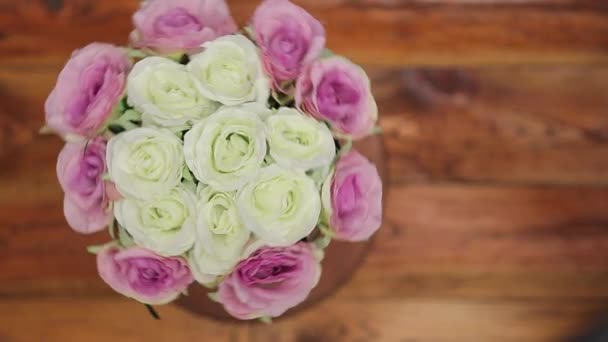 Ein Strauß pastellfarbener Rosen rotiert auf einem Holztisch. Hochzeitskonzept. — Stockvideo