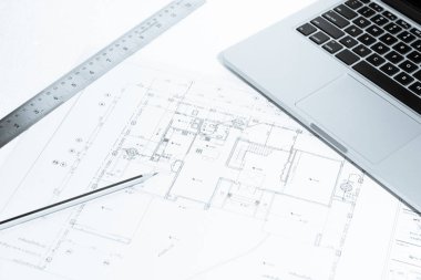 Kalem, metal cetvel ve dizüstü ev inşaat planı üzerinde