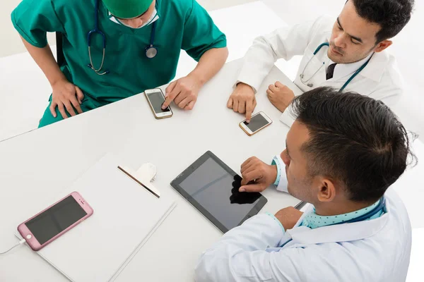 Asiático masculino e feminino médico e enfermeira na mesa olhando para inteligente — Fotografia de Stock