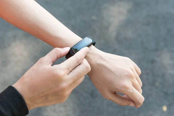 Young Asian female runner putting on heart rate monitor wrist wa