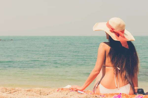 Mooie Aziatische bikini vrouw zittend op strand op zoek naar zee — Stockfoto