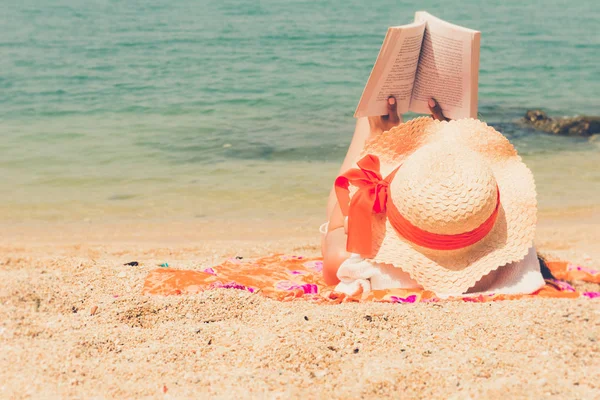 Женщина в бикини сидит на пляже и читает книгу. — стоковое фото