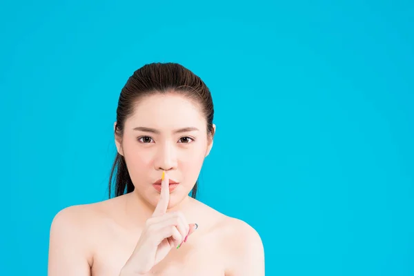 Joven asiática mujer con secreto hush pose aislado en azul backgro —  Fotos de Stock