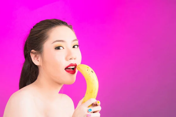 Giovane donna asiatica in possesso di banana isolato in sfondo rosa . — Foto Stock