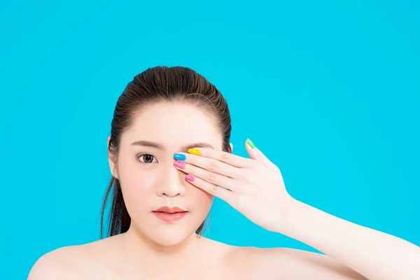 Junge asiatische Frau mit der Hand im Gesicht isoliert auf blauem Hintergrund. — Stockfoto