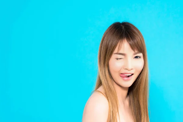 Junge asiatische Frau flirtet isoliert auf blauem Hintergrund. — Stockfoto