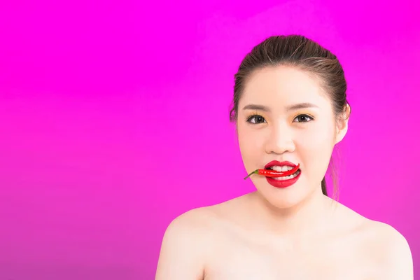 Young Asian woman biting chili isolated in pink background. — Stock Photo, Image