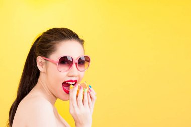 Genç Asyalı kadın turuncu sarı arka planda izole ısırma.