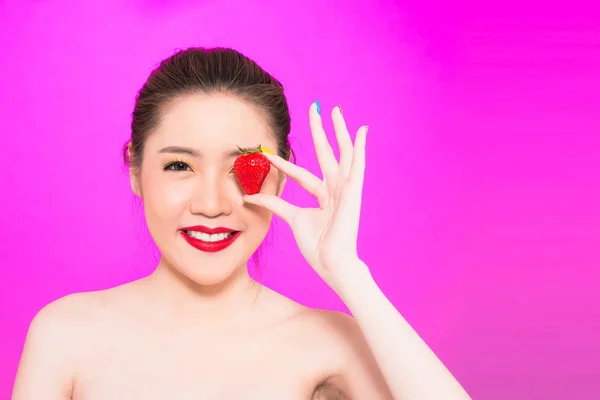 Junge asiatische Frau hält Erdbeere isoliert in rosa Hintergrund — Stockfoto
