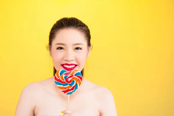 Giovane donna asiatica tenendo lecca-lecca isolato su sfondo giallo — Foto Stock