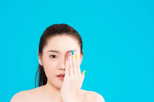 Young Asian woman with hand on face isolated on blue background.