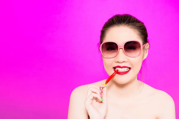 Joven mujer asiática mordiendo chile aislado en fondo rosa . — Foto de Stock