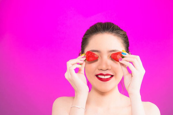 Young Asian woman holding strawberry isolated in pink background