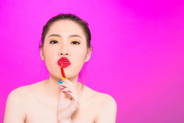 Giovane donna asiatica baciare chili isolato in fondo rosa . — Foto Stock