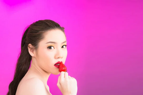 Young Asian woman kissing strawberry isolated in pink background — Stock Photo, Image