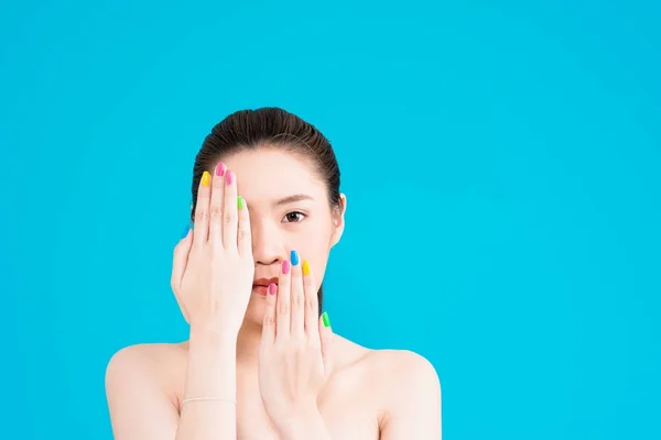 Young Asian woman with hand on face isolated on blue background.