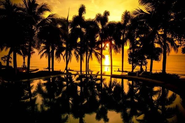 Praia tropical com piscina e palmeiras silhuetas durante o pôr do sol . — Fotografia de Stock