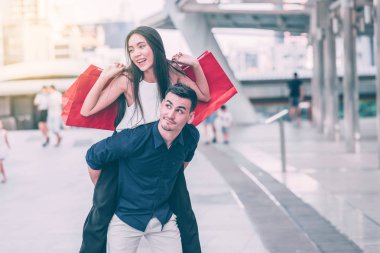 Mutlu çift büyük satış alışveriş Asya ülkesinde zor bir günün ardından tezahürat. Genç yakışıklı beyaz erkek ve çok kırmızı alışveriş çantası arıyorsunuz ile güzel Asyalı kadın tatmin. Kentsel görünüyor uygulamak.