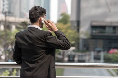 Mobil ofis kavramı. Finansal arka planda bina ile cep telefonu konuşurken yakışıklı başarılı iş adamı veya satış beyazlar. Açık ele alındığında, kentsel görünüyor efekti uygula.