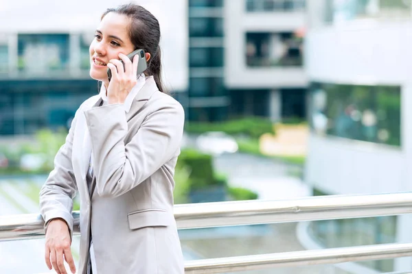 Portrait of business woman on phone. Young professional career business woman standing outside talking on mobile phone. Taken outdoor with natural light. For young woman leadership concept.