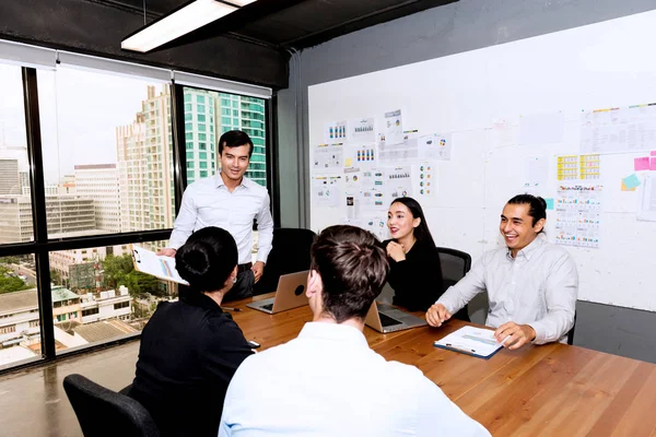 Future business leader concept. Group of young business team discussing work together in modern office. Three handsome white business men and two beautiful women reviewing work in meeting room.