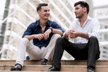 İki mutlu işadamları el sıkışan beton merdiven üzerinde oturuyor. Satılık adam ve sonra başarılı bir anlaşma zor müşterileri ile el sıkışan patronu.