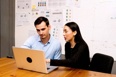 Gelecekteki iş lideri kavramı. Grup genç iş takım iş birlikte modern ofiste tartışıyor. Yakışıklı beyaz iş adamı ve güzel bir Asyalı kadın gözden geçirme iş laptop ile birlikte.