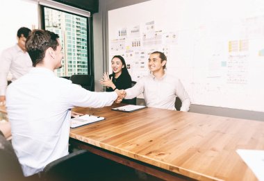 Gelecekteki iş lideri kavramı. Genç iş takım modern ofiste tokalaşırken grubudur. Üç yakışıklı beyaz iş erkek ve güzel kadın Toplantı salonunun içinde anlaşma kapanış.