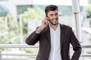 Mobil ofis kavramı. Yakışıklı başarılı beyaz iş adamı veya finansal arka planda bina ile onun cep telefonuyla konuşan Satılık adam. Açık ele alındığında, kentsel görünüyor efekti uygula.